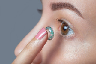 woman inserting blue green contact lens woman inserting blue green contact lens